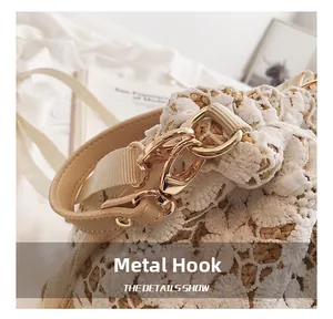 Close-up of light gold metal hooks and white lace detailing on the woven bucket bag