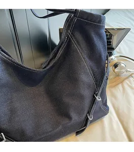 Detailed close-up of dark denim tote bag featuring white contrast stitching and hardware