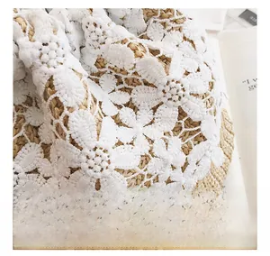 Close-up of delicate white lace crochet detail on a khaki hand-woven straw bucket bag