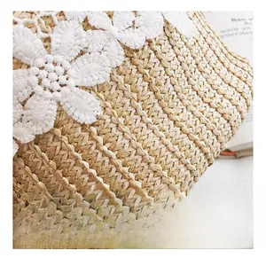 Close-up of woven straw bucket bag with delicate white lace flower embroidery details