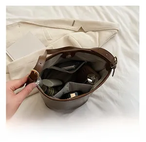 Interior view of brown leather bucket bag showing compartments for phone and cosmetics