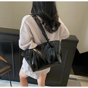 Dettaglio della borsa tote nera lucida con pochette rimovibile e tracolla plissettata