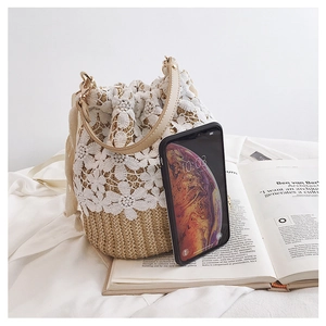 Detail view of lace and straw bucket bag showing size comparison with a smartphone