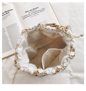 Detail view of straw bucket bag with white lace floral overlay and canvas drawstring liner
