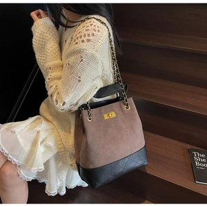 Close-up of vintage quilted bucket bag with chain strap and gold twist-lock closure