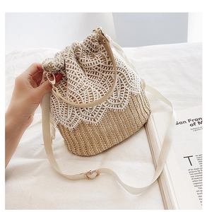 Detail of hand-woven straw bucket bag featuring white lace overlay and adjustable strap