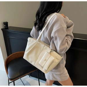 Dettaglio di una borsa tote bianco crema lucida con una piccola pochette quadrata rimovibile