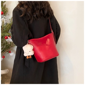 Red leather bucket bag with cute bread plush charm shown on a black winter coat
