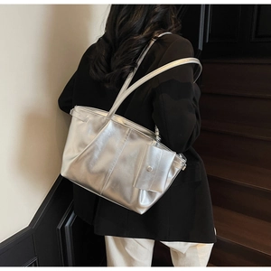 Vista dettagliata della borsa tote argento metallizzato con ciondolo su scala moderna