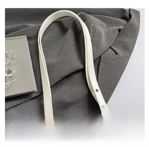 Détail de la bandoulière en cuir blanc avec boucles en métal argenté et coutures nettes
