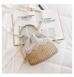 Close-up of beige straw bucket bag with white lace floral trim and soft drawstring closure