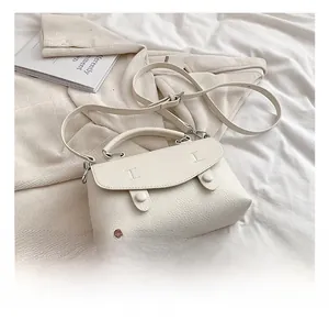 Dettaglio ravvicinato della borsa bianco crema in pelle martellata con patta e fibbie tonde