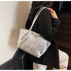 Dettaglio della borsa tote argento metallizzato con mini pochette portata sulla spalla