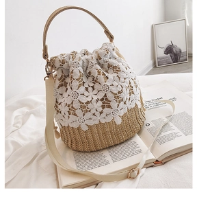 Detail of straw bucket bag featuring white lace floral embroidery and drawstring closure