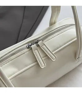 Gros plan sur la double fermeture éclair et la texture en cuir blanc mat du sac à main