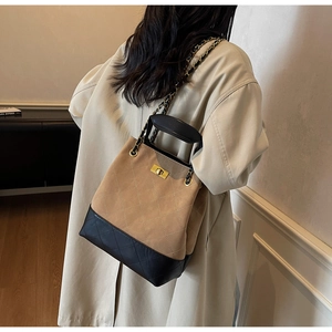 Detailed view of women's quilted bucket bag in camel and black with metal chain strap