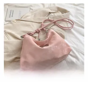 Detailed shot of pink suede tote bag with silver bow charm and knotted cord straps