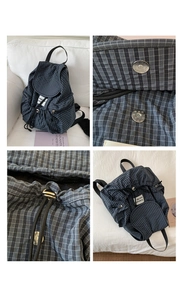 Detail of navy plaid texture, drawstring closure, and magnetic snap on a soft casual backpack