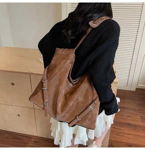 Detailed view of dark brown tote bag with vintage leather texture and metal buckle accents