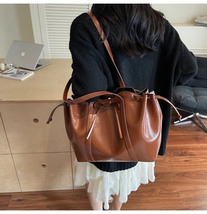 Close-up of brown glossy leather shoulder bag with drawstring and ribbon detail