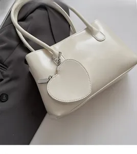 Dettaglio borsa baguette in pelle bianco crema con ciondolo portamonete a cuore