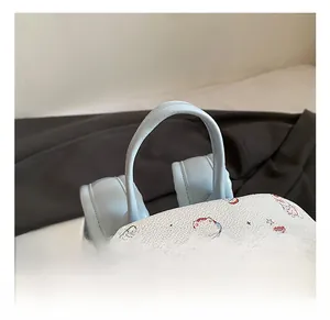 Détail du sac à dos blanc à motifs avec double fermeture éclair et poignée bleu clair