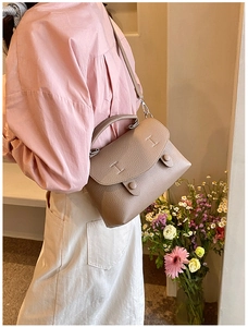 Borsa a tracolla in pelle motivo litchi indossata da modella con decoro floreale