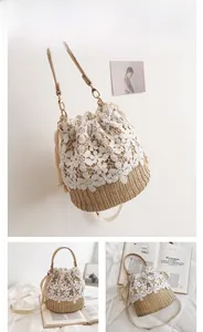 Detailed view of woven straw bucket bag with delicate white floral lace and leather strap