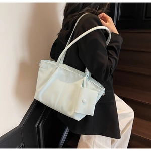 Borsa tote verde chiaro minimalista con pochette coordinata portata a spalla in scena quotidiana