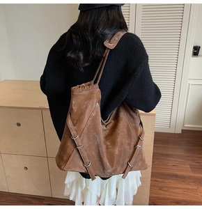 Detail view of large brown vintage tote bag featuring side metal buckles and straps