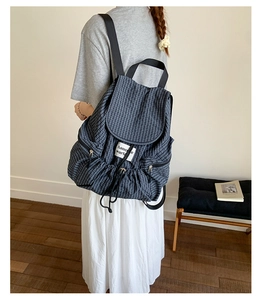 Detail of navy plaid backpack showing drawstring closure and textured woven fabric