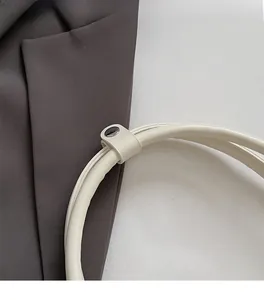 Dettaglio della borsa in pelle bianca con anelli in metallo argento e manico cilindrico
