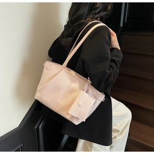 Dettaglio di una borsa tote crema in pelle cerata con un piccolo astuccio coordinato