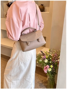 Borsa a tracolla in pelle color talpa martellata indossata da modella in ambiente elegante