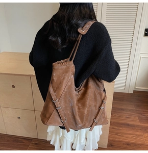 Close-up of brown vintage leather shoulder bag with textured finish and side buckle detail