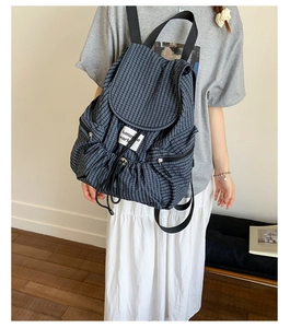 Detailed view of black plaid backpack with drawstring closure and vintage flap design