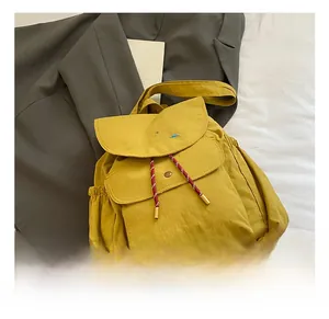 Détail du sac à dos en toile jaune moutarde avec broderie et cordons bicolores