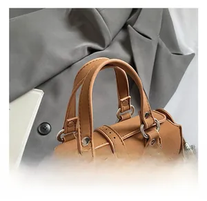 Close-up of comfortable handle on brown suede Boston bag with metallic hardware