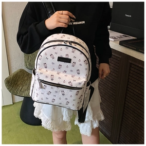 Gros plan d'un sac à dos blanc avec motifs de lapins violets tenu par un mannequin en intérieur