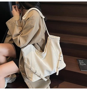 Detail of a large cream leather shoulder bag featuring adjustable strap and silver rings