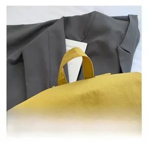 Détail de la poignée renforcée et de la texture du tissu sur le sac à dos jaune
