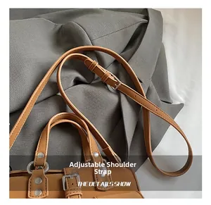 Detail of adjustable shoulder strap and metal hardware on brown moto style handbag