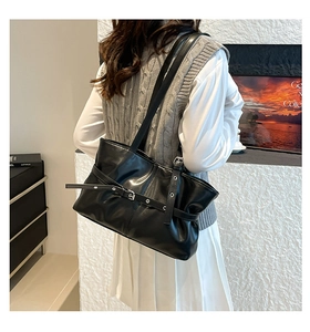 Détail d'un sac cabas en similicuir noir avec bandoulière à boucle porté par un mannequin
