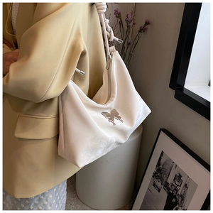 Detail of silver butterfly ornament and rope knot strap on white satin tote bag