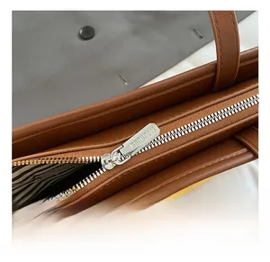 Detail of high-quality zipper hardware and striped lining on brown leather bucket bag