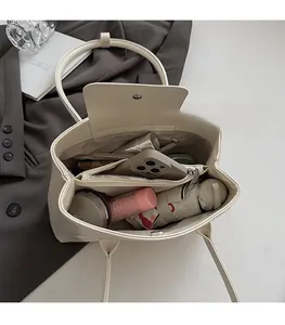 Vista interna della borsa sottobraccio beige minimalista con ampi scomparti portaoggetti
