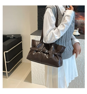 Détails des plis verticaux et de la boucle en métal sur le sac cabas marron foncé