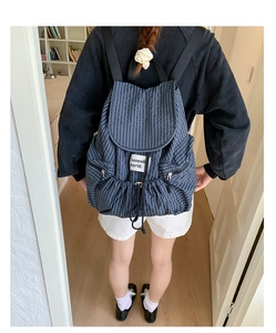 Detail of navy blue plaid drawstring backpack with flap closure and side pockets