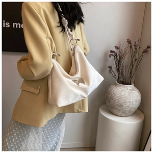 Detail of a beige velvet tote bag with a silver butterfly buckle and woven rope strap