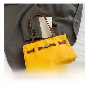 Close-up of yellow nylon tote with brown leather trim and silver twist lock buckle
